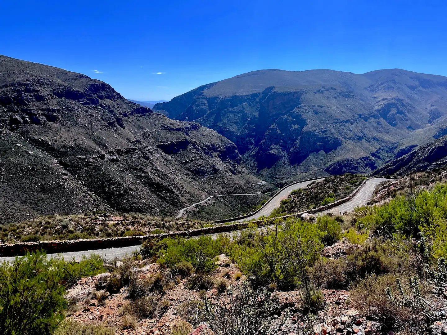Gravel switchbacks with dry-stone retaining walls climbing a mountain pass